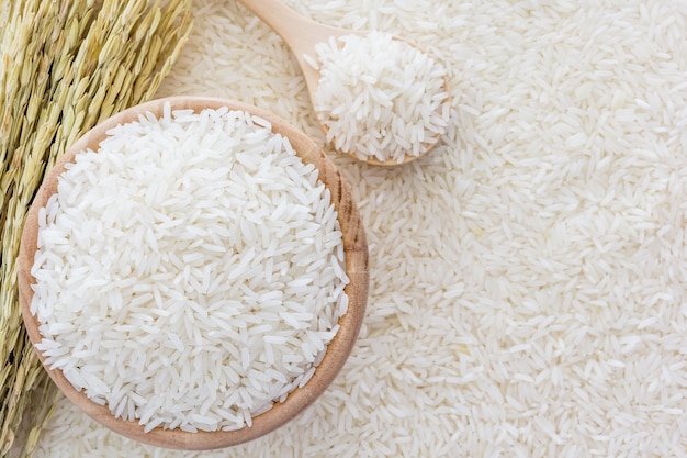 Photo white rice in bowl and a bag, a wooden spoon and rice plant on white rice background