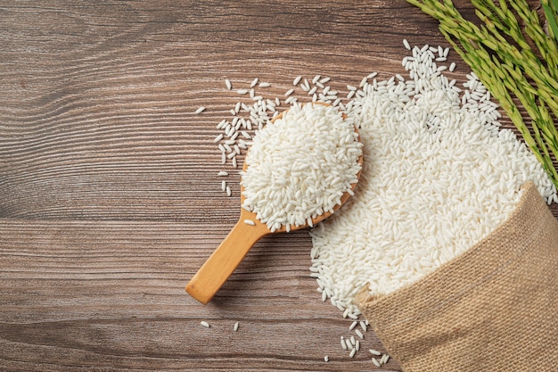 Free photo sack of rice with rice on wooden spoon and rice plant