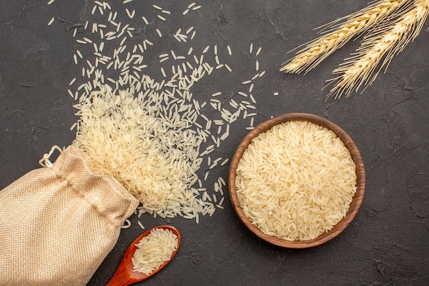 Free photo top view of raw rice inside bag and plate on grey surface